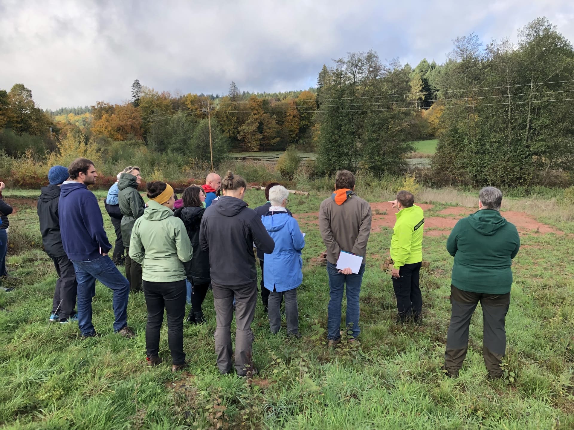 Erwachsene stehen auf einem Feld und nehmen an einer Führung mit einem Naturpark Guide teil