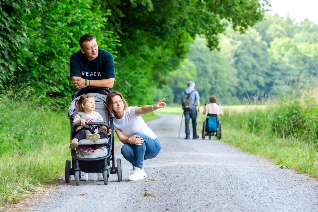 Eltern mit Kind im Kinderwagen unterwegs auf dem Komfortwanderweg